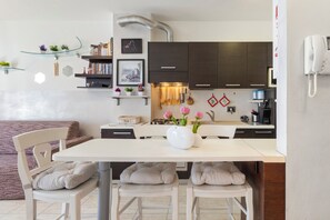 A modern kitchen with a dining table, chairs, and a vase with flowers. - Cuddly House - 2 Terrazzi, Parking, pet Friendly (Cividale del Friuli)