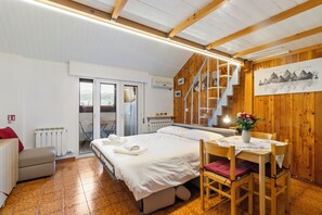 A bedroom with a bed, a chair, a table, and a view of the outdoors through a sliding door. - Mountain Nest - Netflix - Pet Friendly - Parking (Tarvisio)