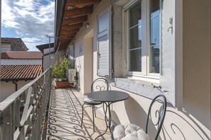 Een balkon met een tafel en stoelen, een bloempot en uitzicht op de lucht.