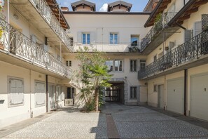 A courtyard with a central tree, surrounded by buildings with balconies and shutters. - Casa Giulia - con Parcheggio Privato e Terrazza (Gorizia)