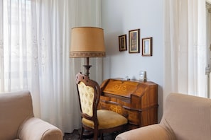 A room with a wooden desk, a lamp, two upholstered chairs, and a wall with three framed pictures. - Dimora Manzoni - per 5 pp, Parcheggio e Ascensore (Gorizia)
