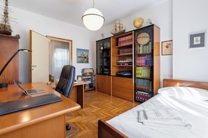 A well-organized bedroom with a wooden desk, a laptop, a chair, a bed with white bedding, a bookshelf with books, and a globe on the wall. - Dimora Manzoni - per 5 pp, Parcheggio e Ascensore (Gorizia)
