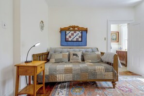 A bedroom with a wooden bed, a bedside table with a lamp, a quilt, a patterned rug, and a wall-mounted quilt. - Sauna & Fire Pit, Quiet 2-Unit Combo in Broadway (Broadway)