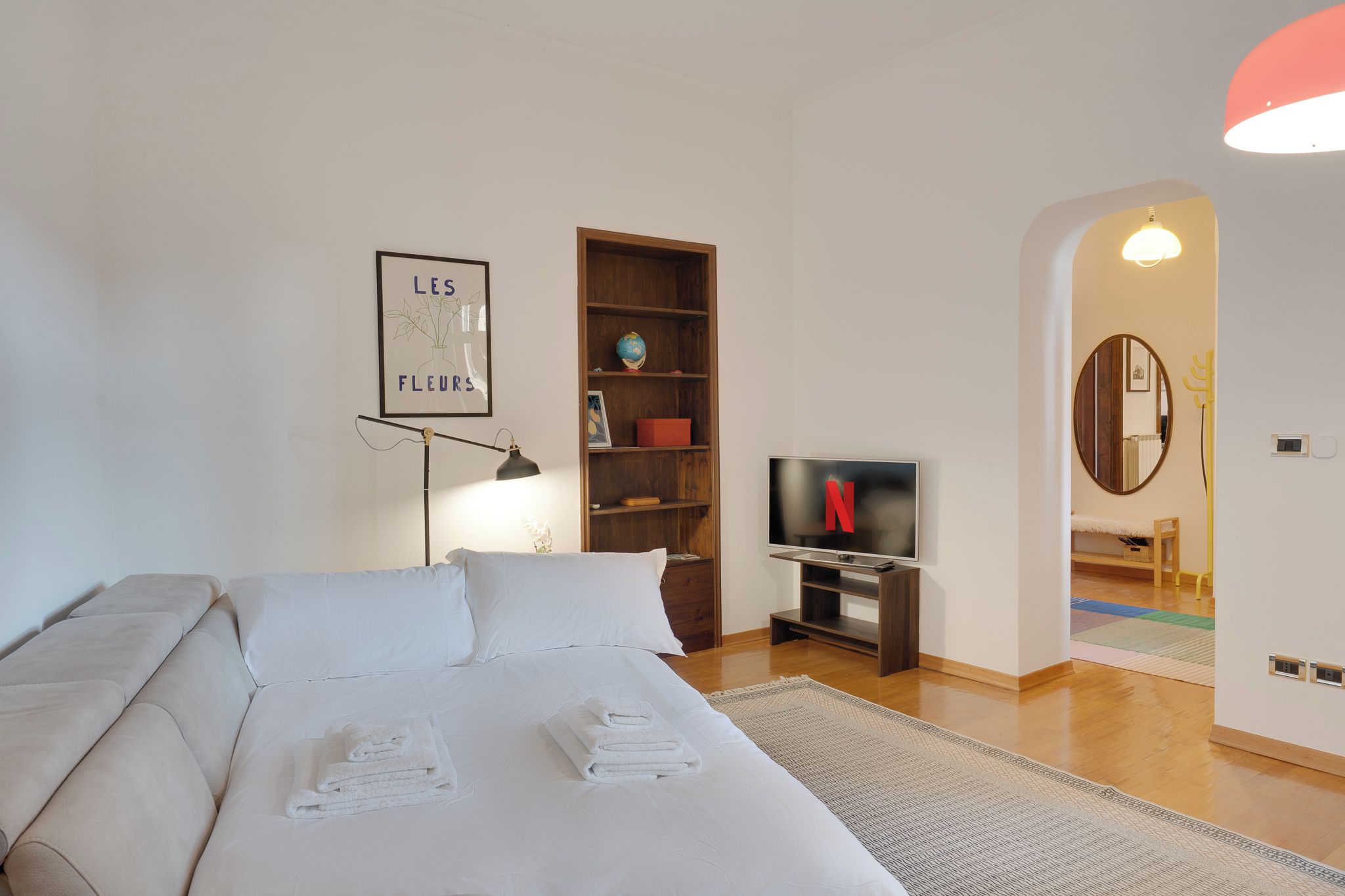 A bedroom with a bed, a desk, a TV, a bookshelf, and a framed picture on the wall.