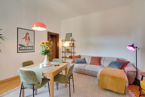 A modern living room with a dining area, a sofa, a coffee table, and a bookshelf.