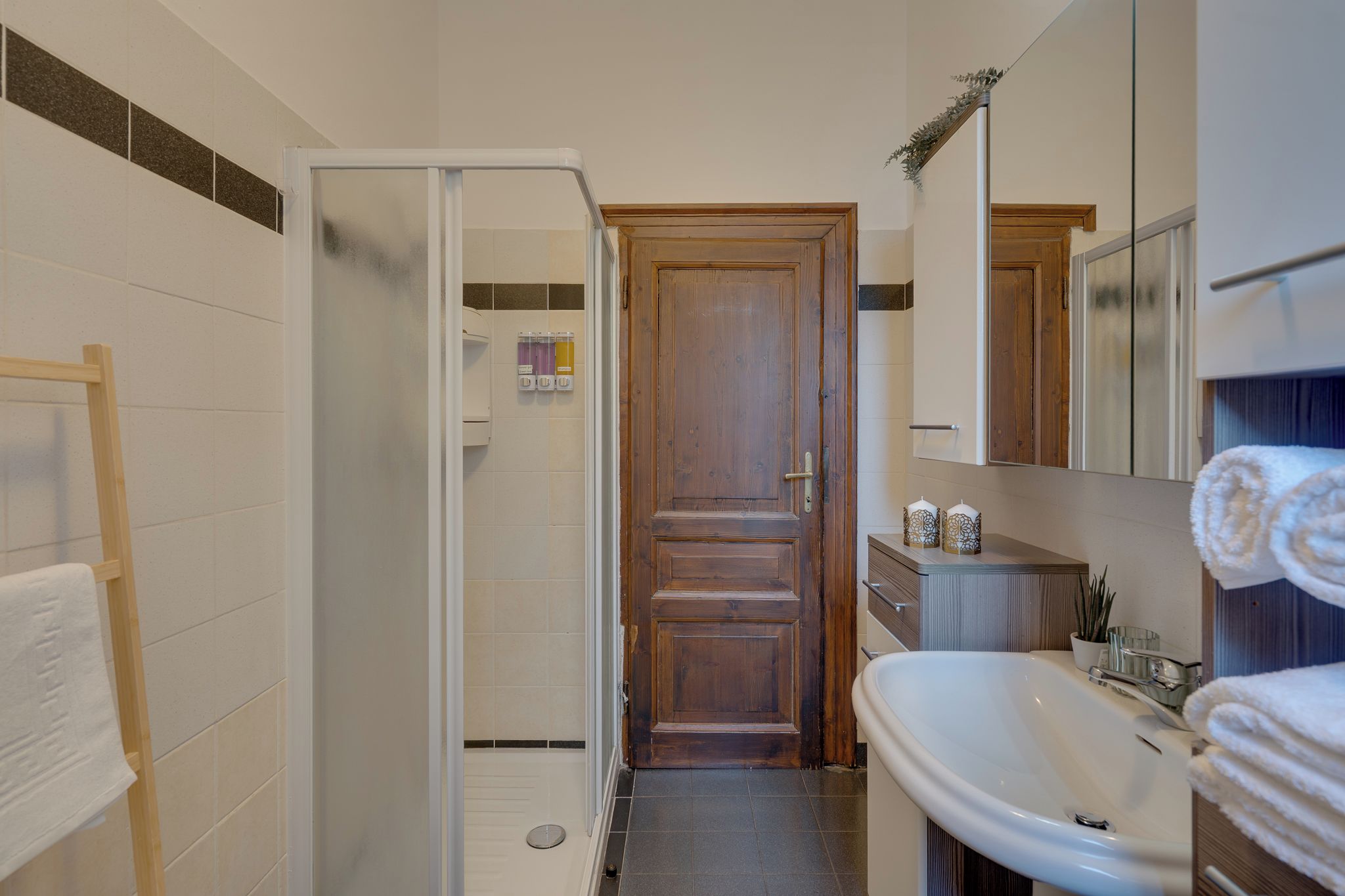 A bathroom with a wooden door, a white sink, and a towel rack.