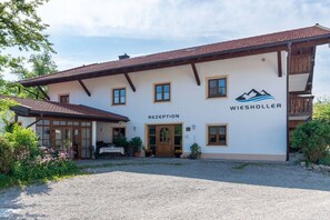 Ein zweistöckiges Gebäude mit einer Rezeption, auf der 'WIESHOLLER' steht, und einem Berglogo.