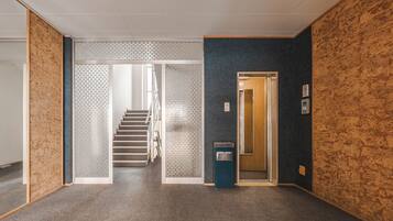 A hallway with a carpeted floor, a staircase, and a door leading to another room.