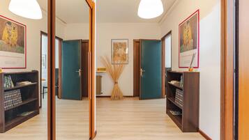 A hallway with wooden doors, a central table with a map, and framed artwork on the walls.