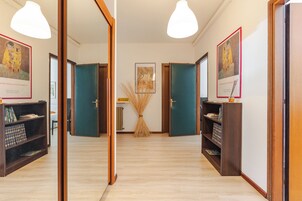 A hallway with wooden doors, a central table with a map, and framed artwork on the walls.