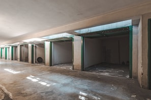 Un pasillo con puertas abiertas que dan a habitaciones, piso de concreto y techo con vigas a la vista.