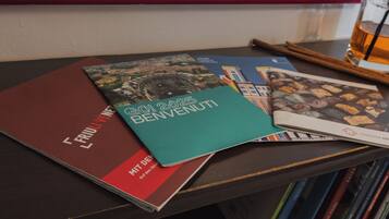 A stack of books on a table with a framed picture in the background.