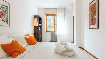 A hotel room with a bed, a nightstand, a wardrobe, a window, and a framed picture on the wall.