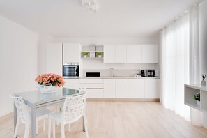 Una cocina moderna con armarios blancos, una mesa de comedor con sillas y una planta en maceta sobre la mesa.