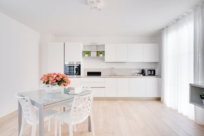 A modern kitchen with white cabinetry, a built-in oven, and a microwave.