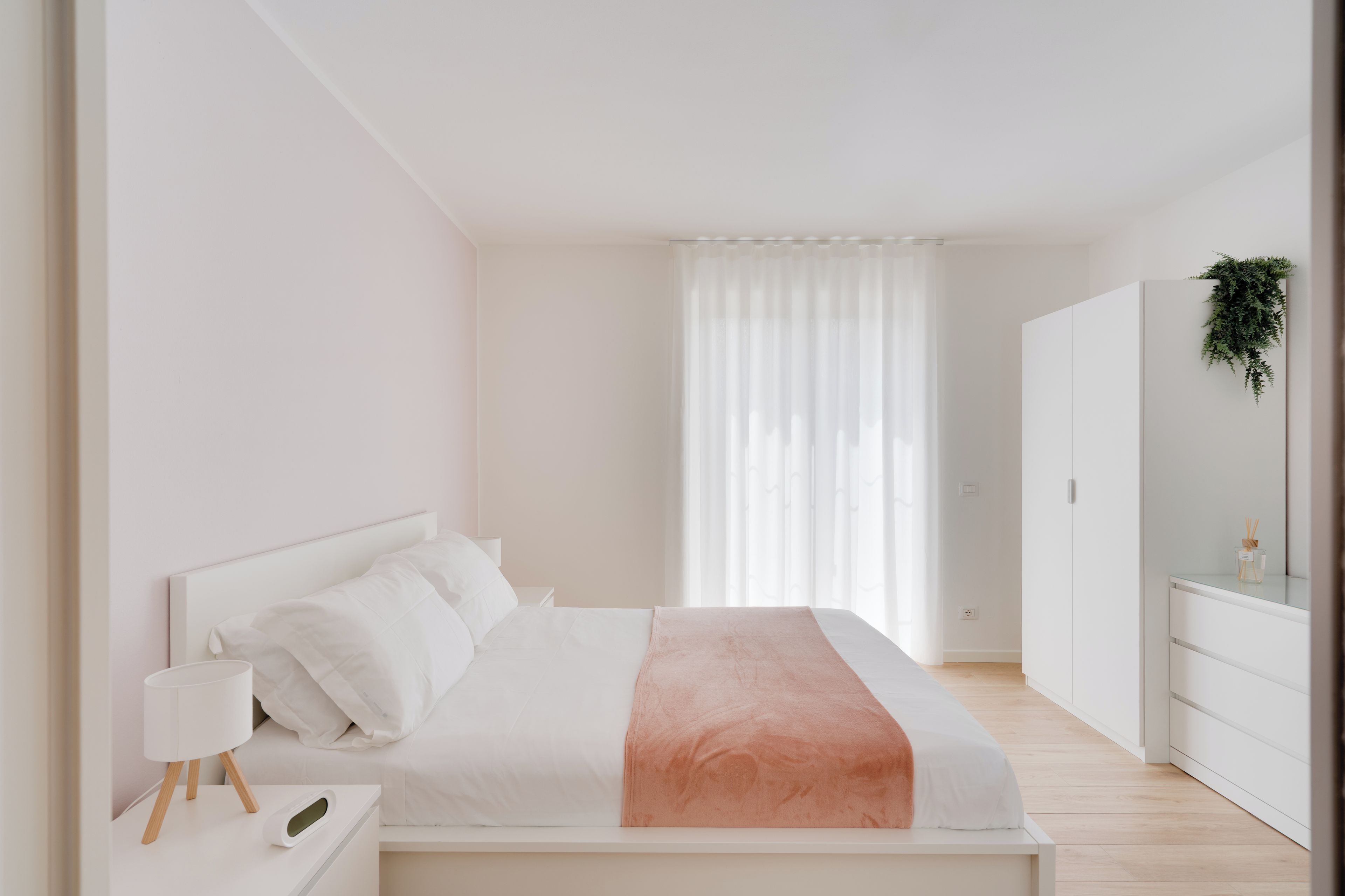 Un dormitori minimalista amb llit, taula de nit i prestatge.