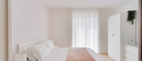 A minimalist bedroom with a bed, bedside table, and a dresser.