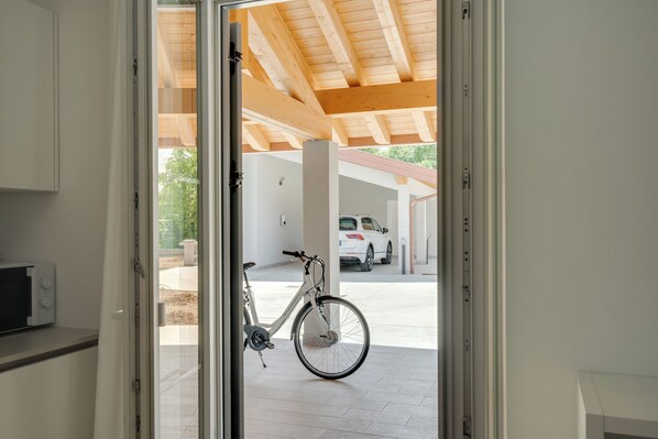 A bicycle parked inside a building with a view of a parking area outside.
