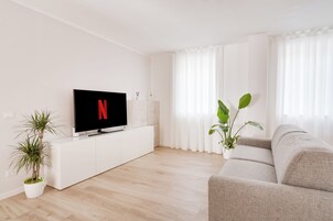 Una sala de estar moderna con un televisor de pantalla plana, un sofá y plantas en macetas.