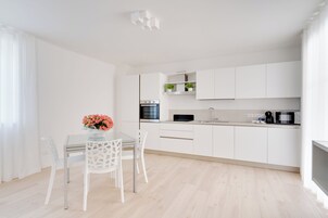 Una cocina moderna con armarios blancos, una mesa de comedor con sillas y un florero con flores.
