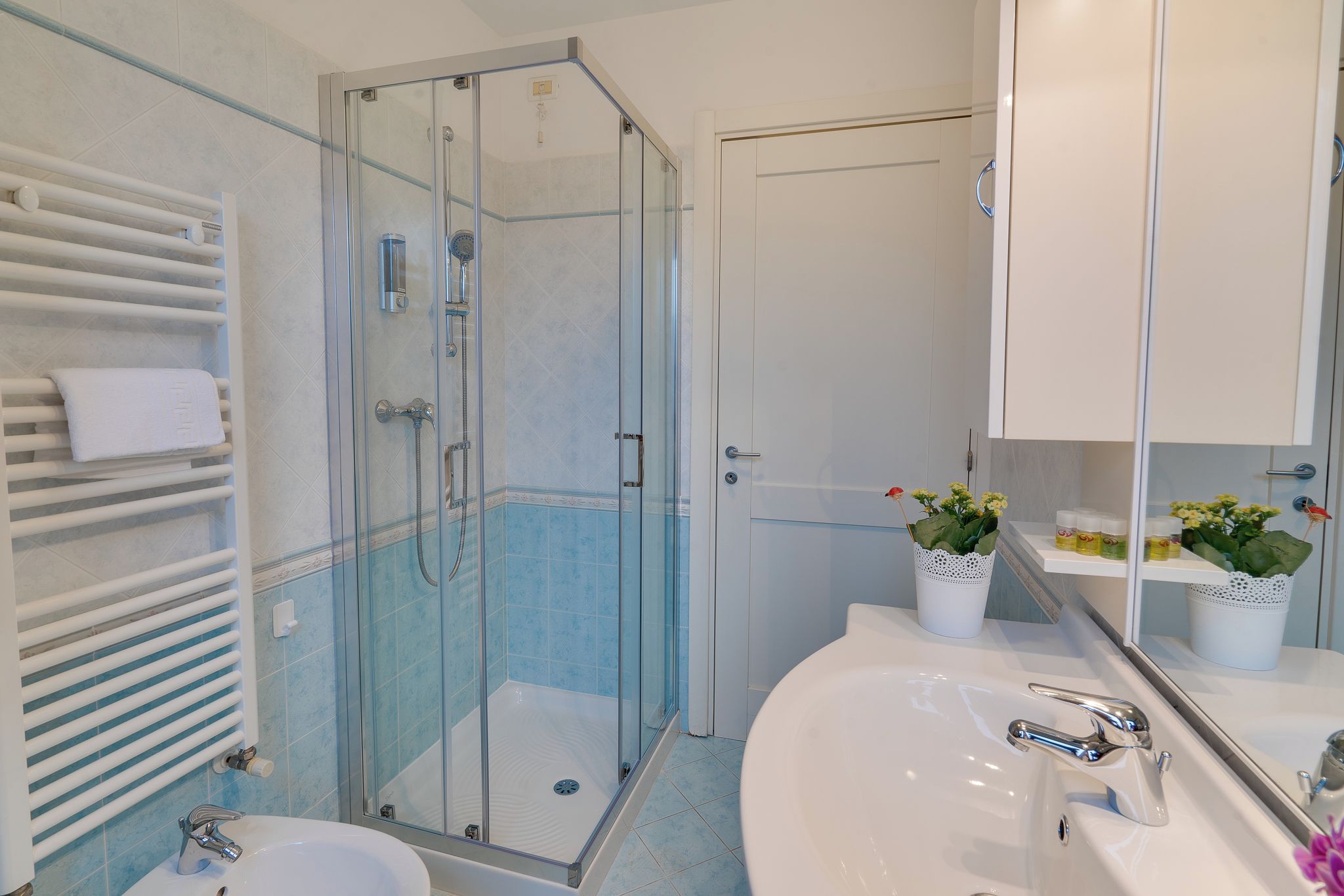 Un bagno moderno con doccia vetro, lavandino bianco e specchio con pensile.