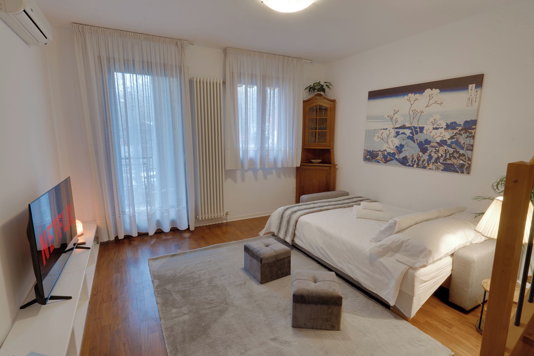 A bedroom with a bed, a TV, a cabinet, and a painting.