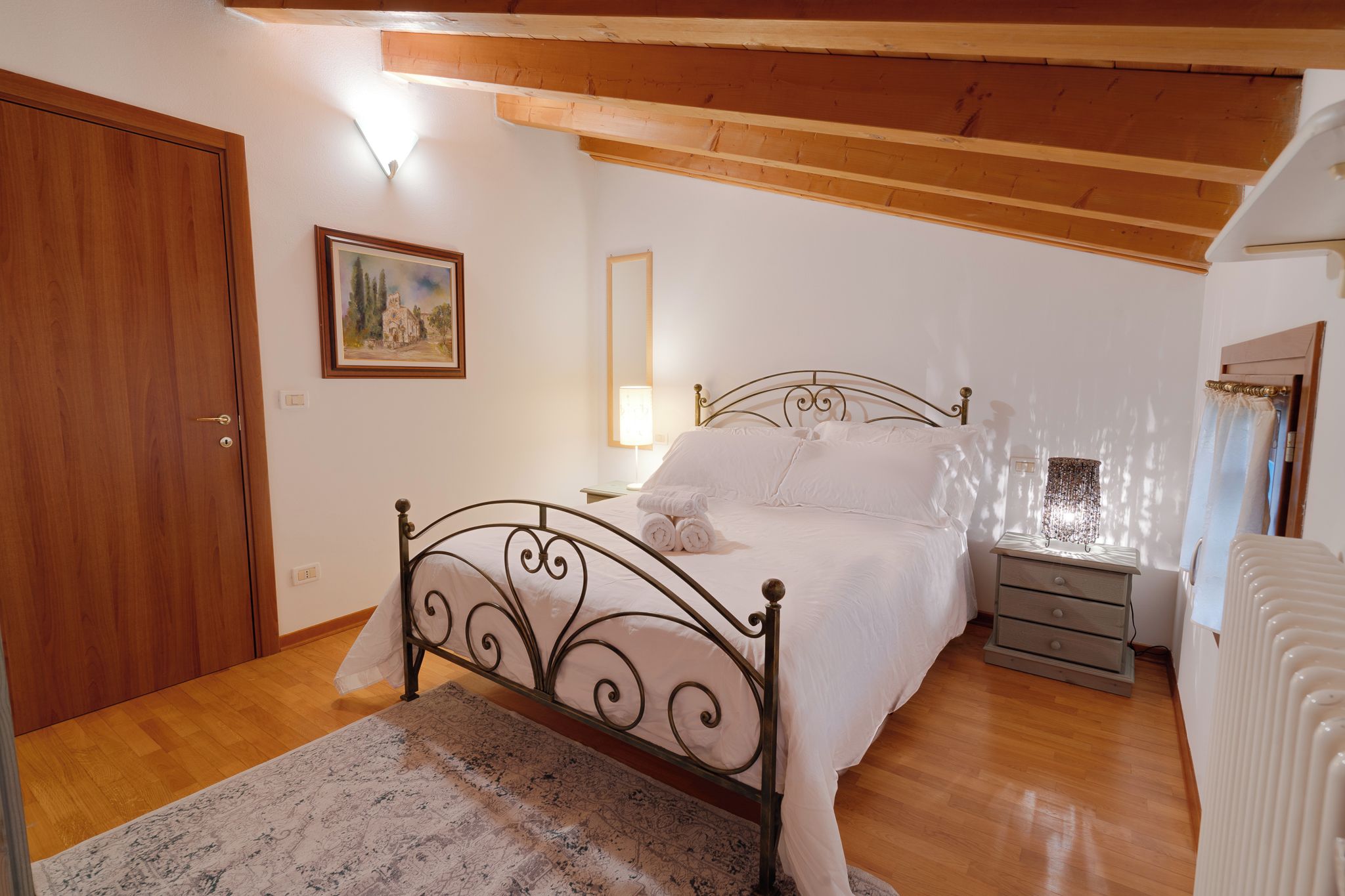 Una camera da letto con un letto, un comodino, una lampada e un quadro appeso al muro.