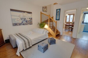 Un dormitorio con cama, mesita de noche, lámpara y un cuadro en la pared.