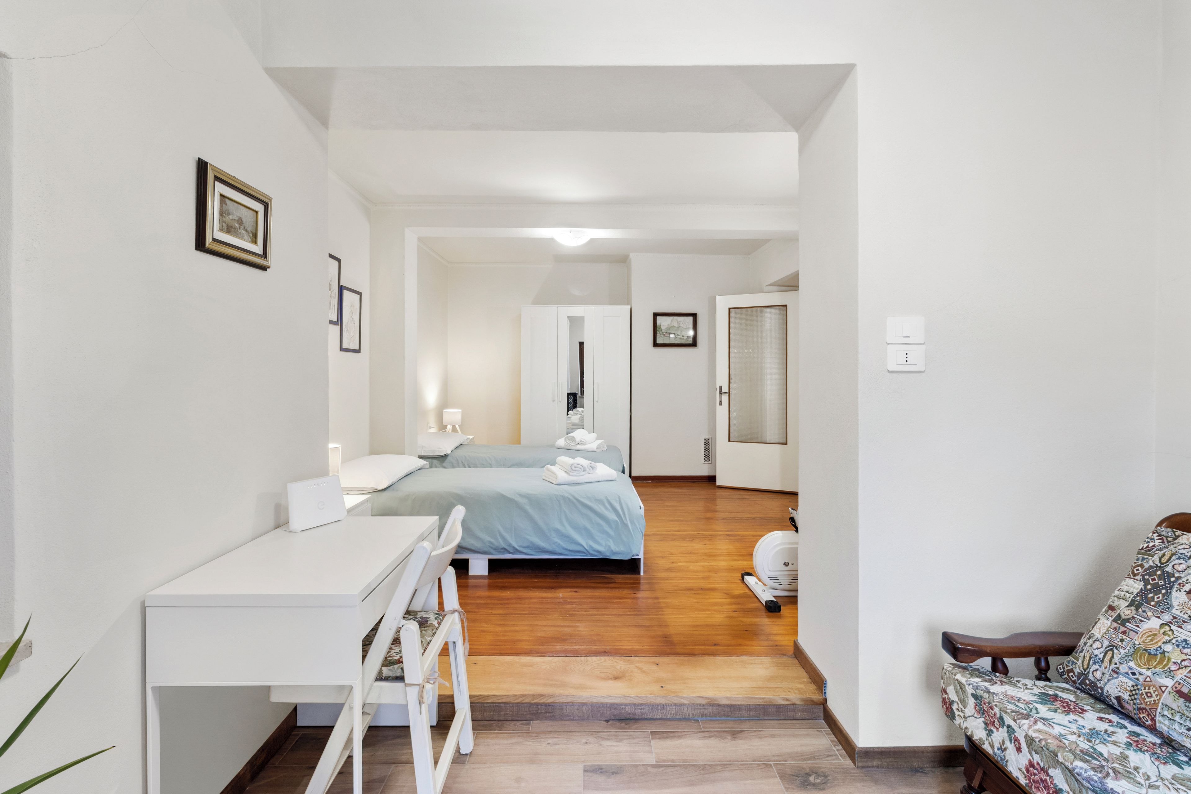 Una habitación de hotel con cama, escritorio, silla y una mesita.