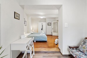 A hotel room with a bed, a desk, a chair, and a small table.