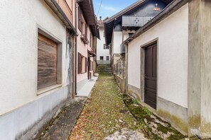 A narrow alleyway between buildings with stone steps leading up to a wooden door. - La Petite Maison - Near Zoncolan and Sappada (Rigolato)