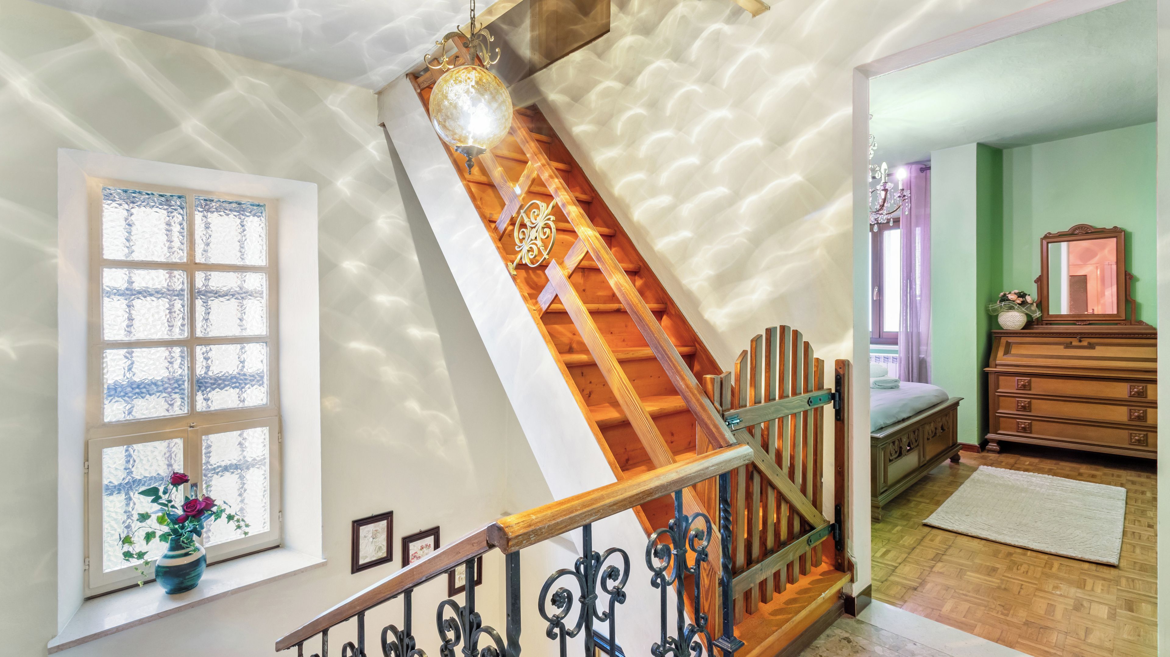 Una escalera con barandilla de madera y una lámpara de globo decorativa.