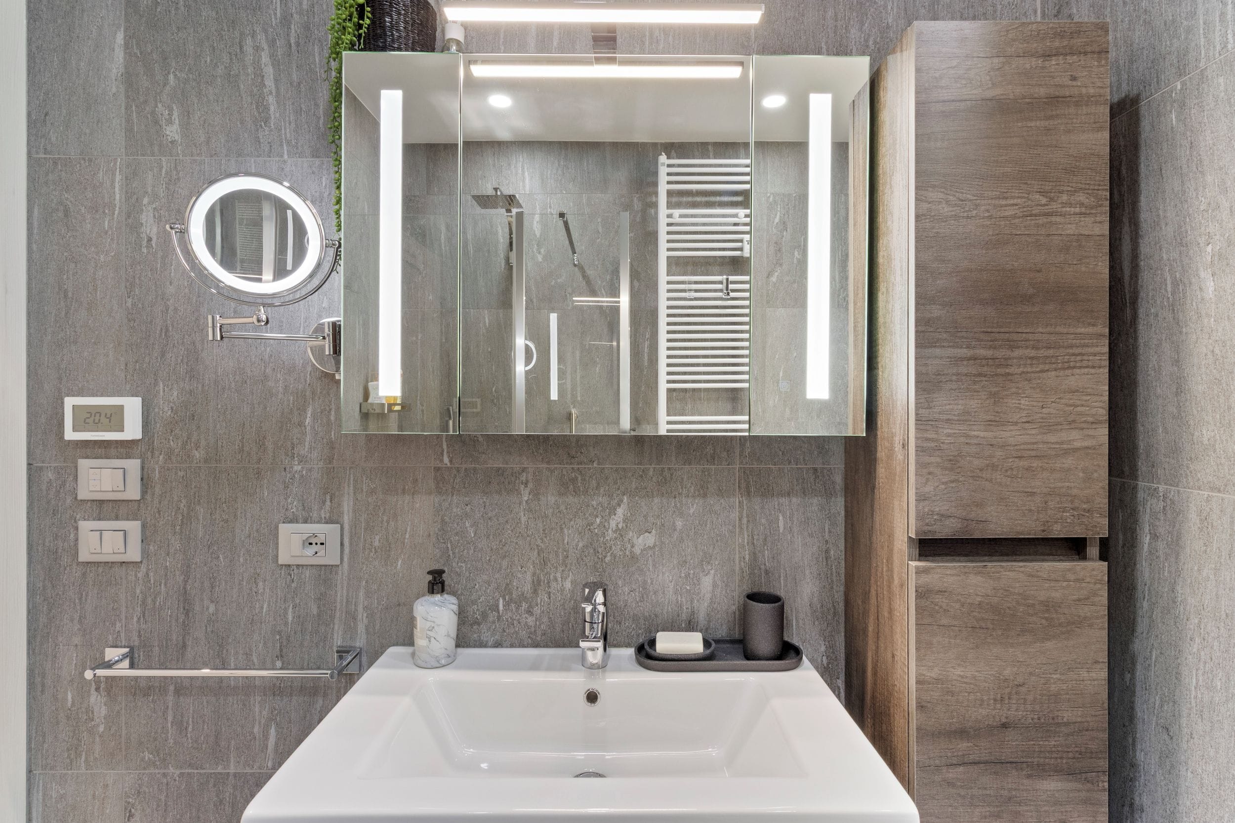 A modern bathroom with a large mirror, a built-in shower, and a white sink.