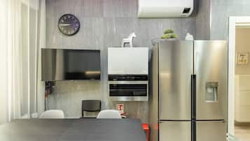 Een moderne keuken met een ingebouwde koelkast, een aan de muur bevestigde televisie en een klok.