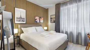 Ein Hotelzimmer mit einem großen Bett, einem Nachttisch mit Lampe, einem Spiegel und Holzvertäfelung.