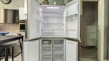 Una cocina moderna con refrigerador integrado, una mesa de comedor y un reloj en la pared.