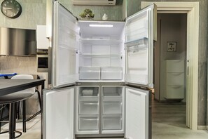 Una cocina moderna con refrigerador integrado, una mesa de comedor y un reloj en la pared.