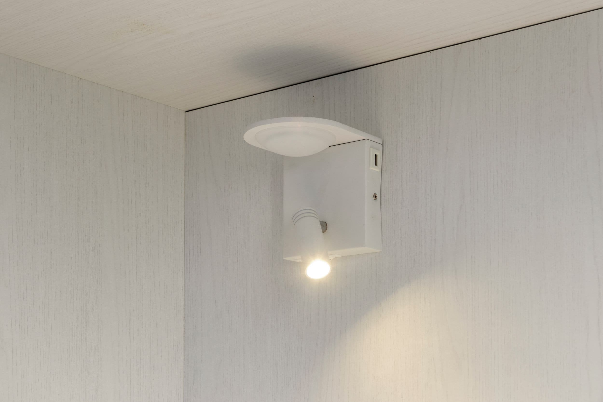 A white wall with a recessed ceiling light fixture.