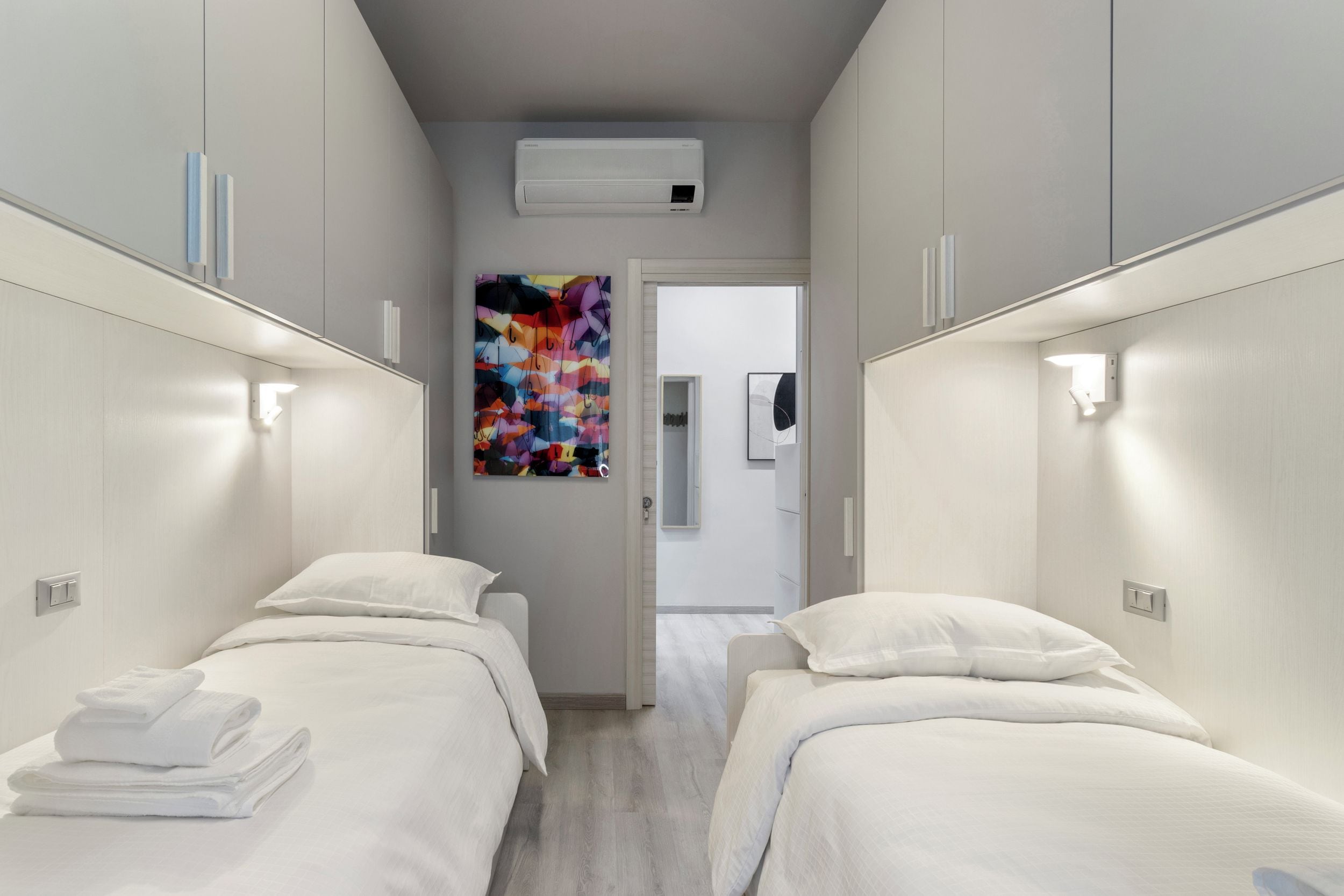Une chambre d’hôtel avec deux lits, une peinture abstraite aux couleurs vives et un appareil de climatisation.