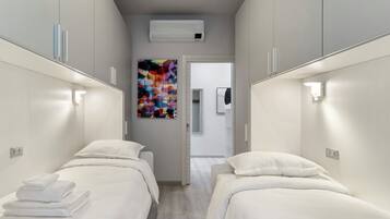 Une chambre d’hôtel avec deux lits, une peinture abstraite aux couleurs vives et un appareil de climatisation.