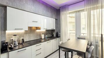 A modern kitchen with white cabinets, a black countertop, and a dining area with a table and chairs.
