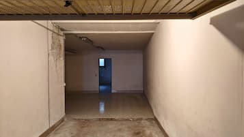 A narrow hallway with a tiled floor and a door at the end leading to another room.
