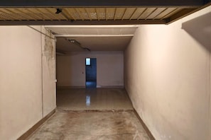 Un pasillo estrecho con piso de baldosas y una puerta al final que da a otra habitación.
