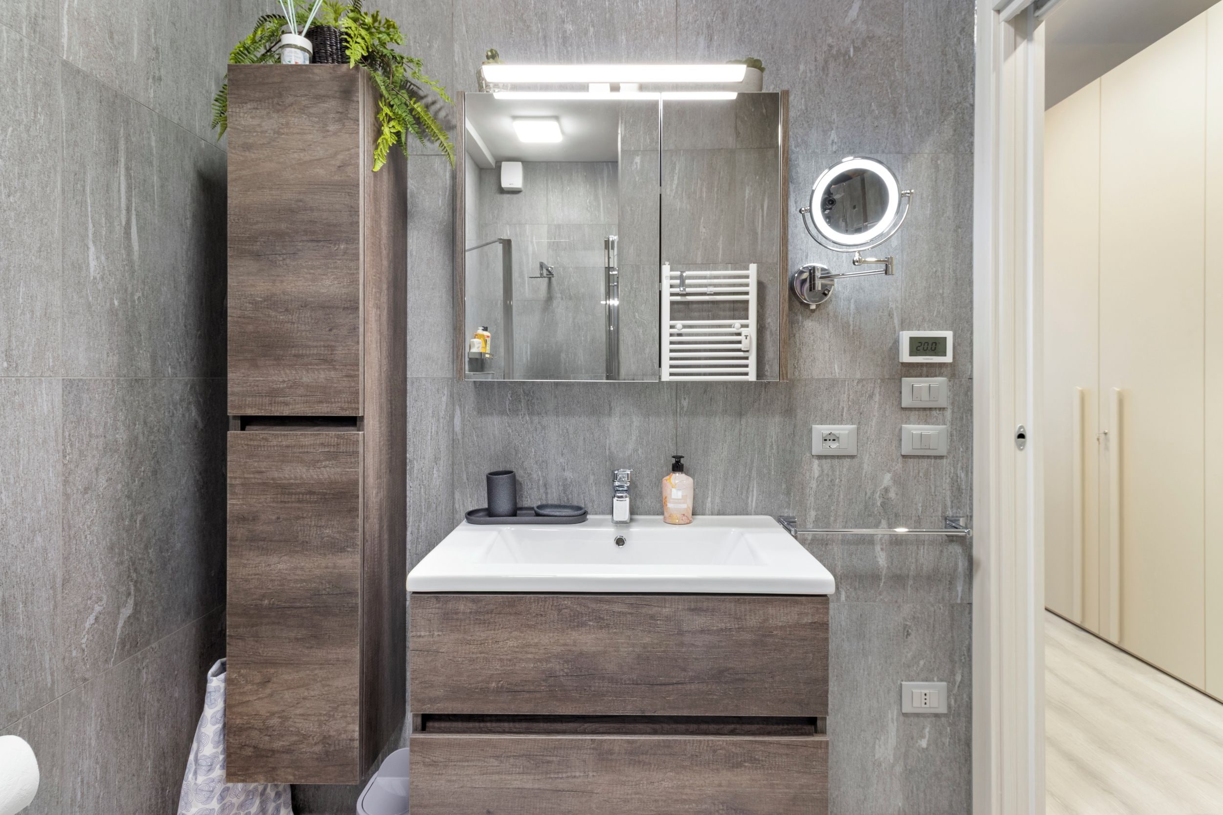Een moderne badkamer met een houten wastafel, een grote spiegel, een ingebouwde verwarming en een toilet.