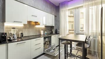 A modern kitchen with white cabinets, a built-in dishwasher, and a coffee machine.