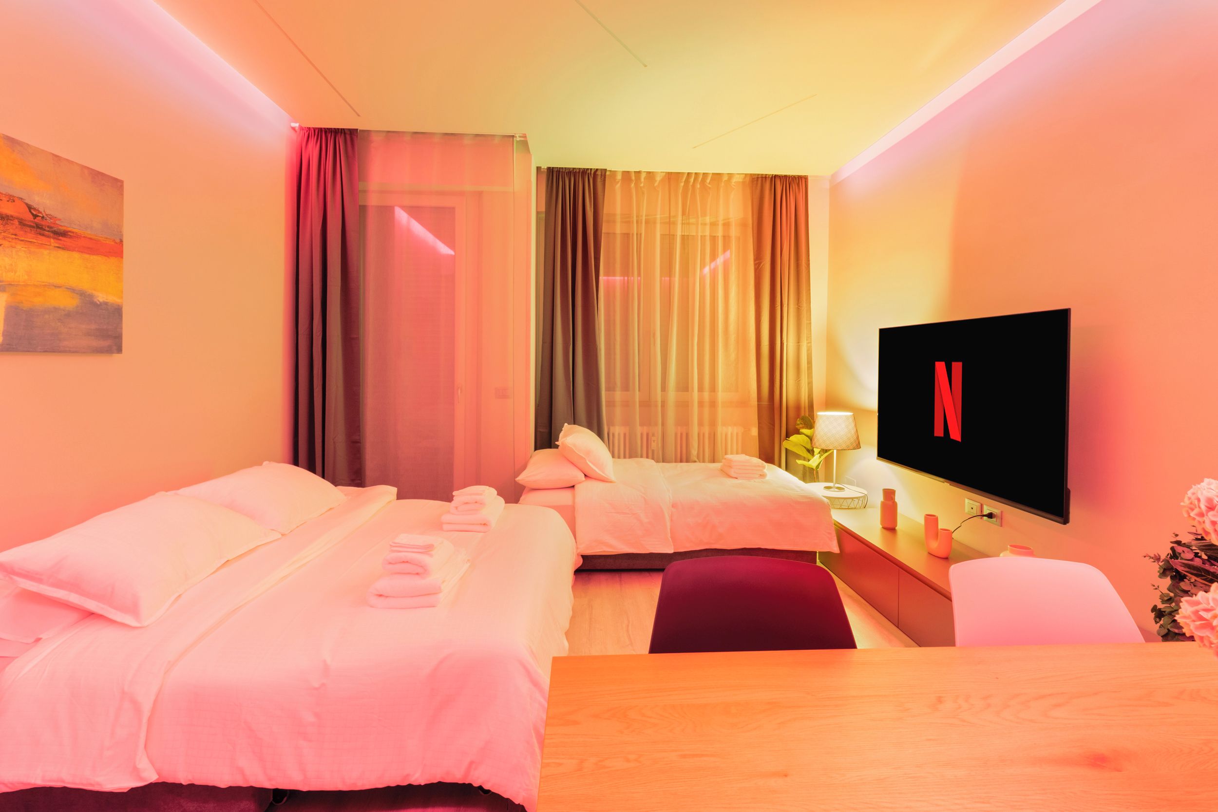 Habitación de hotel con dos camas, un escritorio, un televisor y un cuadro en la pared.