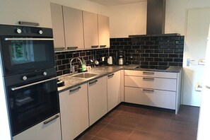 Une cuisine moderne avec des armoires blanches, des appareils électroménagers noirs et un dosseret de carrelage noir.