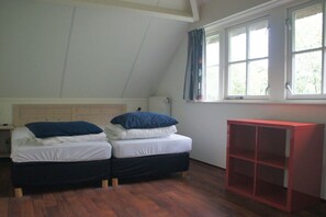 A room with two beds, a red cabinet, and a window with curtains. - Holiday home with 3 bedrooms (Burgh-Haamstede)