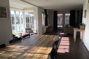 Un vaste espace de vie comprenant une grande table à manger en bois, des sièges confortables et une cheminée.