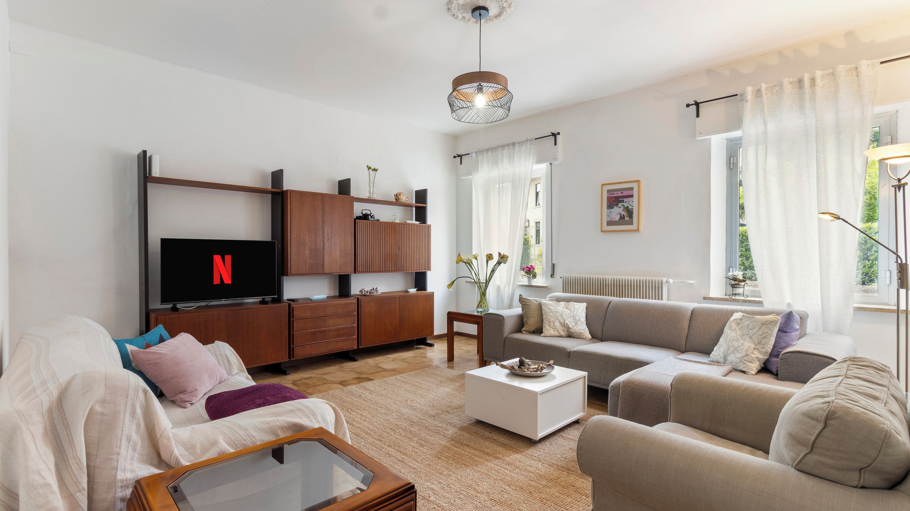 Ein modernes Wohnzimmer mit Fernseher, Holzmöbeln, einem Couchtisch und einer Couch.
